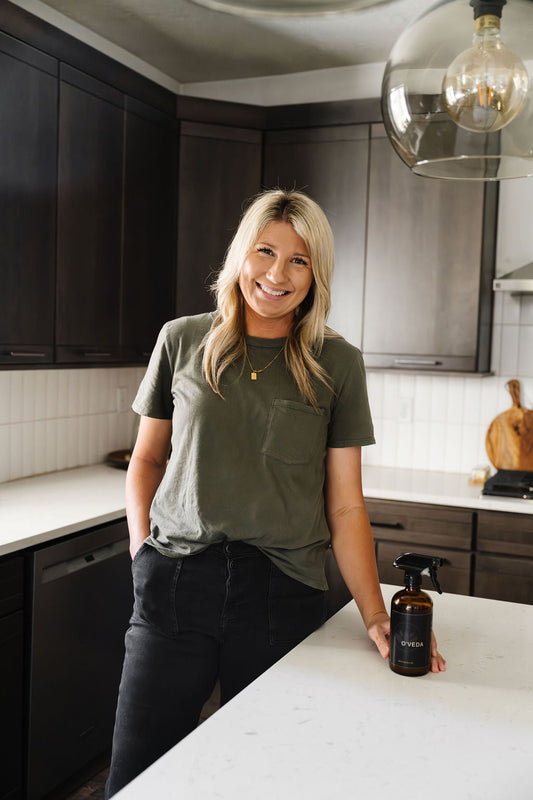 Sami, founder of O'Veda, reading a cleaning product ingredient label in her kitchen